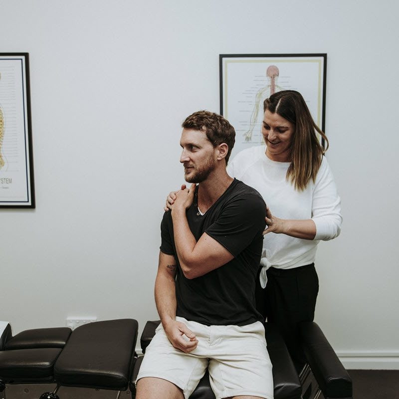 Chiropractor working with a man suffering from shoulder pain.